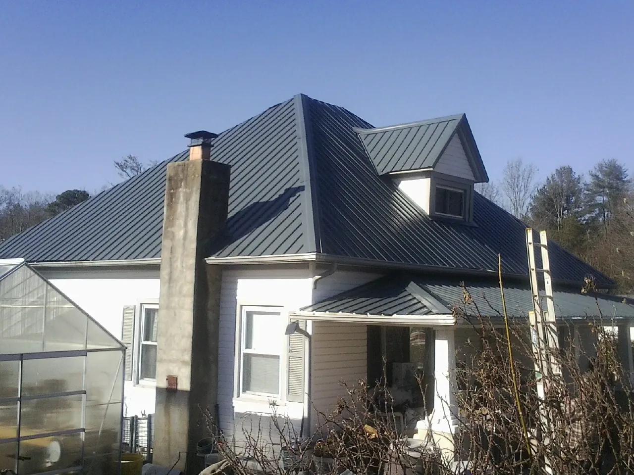 Dark blue standing seam metal roof on a white farmhouse with dormer — Slate & Tile Roof Repair by Roofing Brothers in Battle Ground