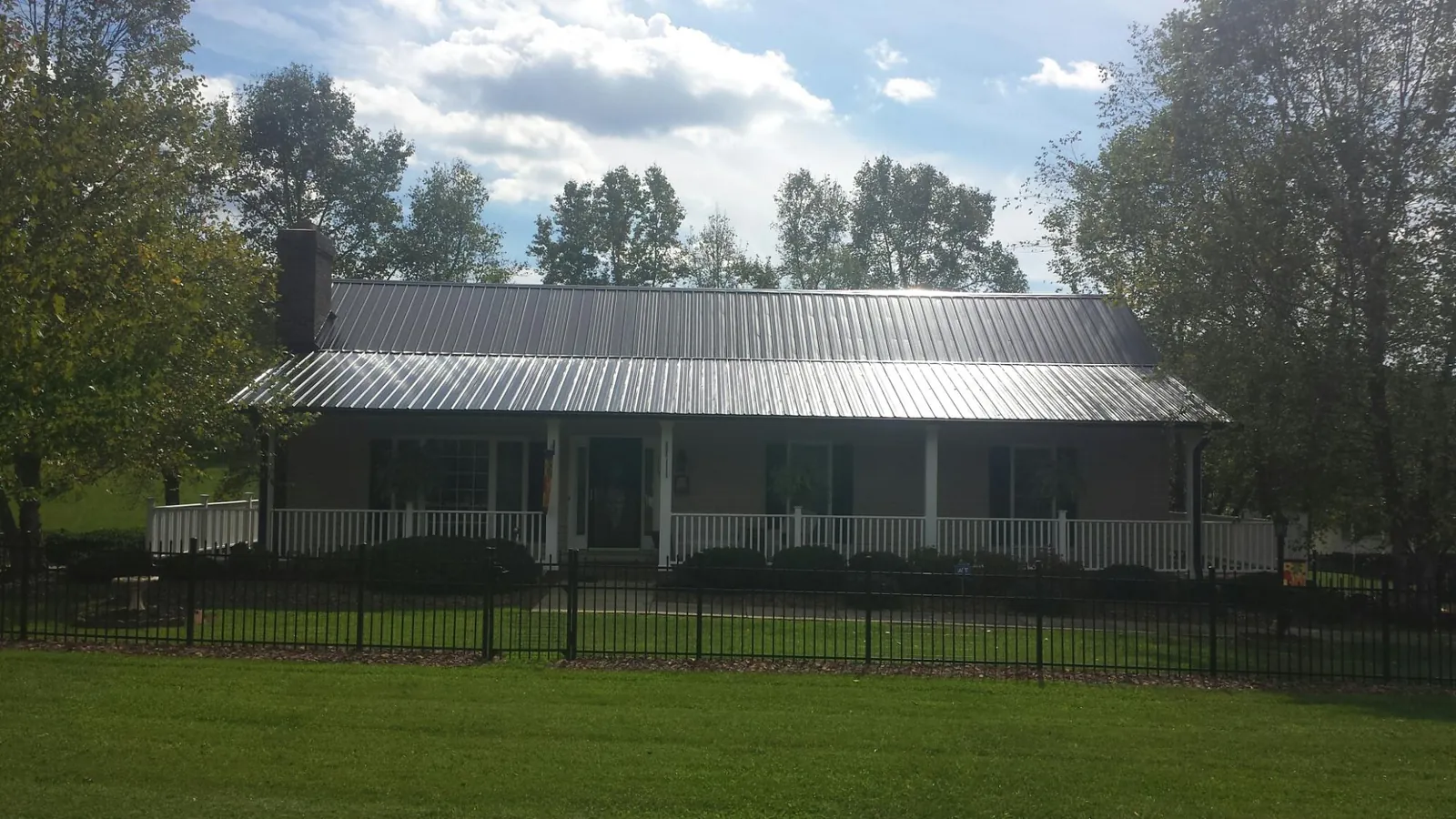 Gray metal roof on a brick ranch with a full width front porch — Gutter Guard Installation work by our crew in Battle Ground