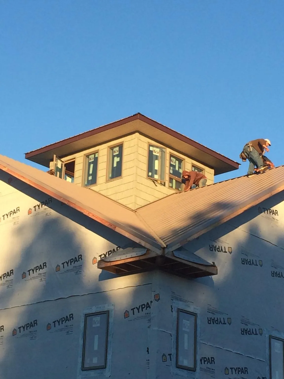 Roofers working around a rooftop cupola on a new metal roof at sunset — Roof Waterproofing in Battle Ground by Roofing Brothers
